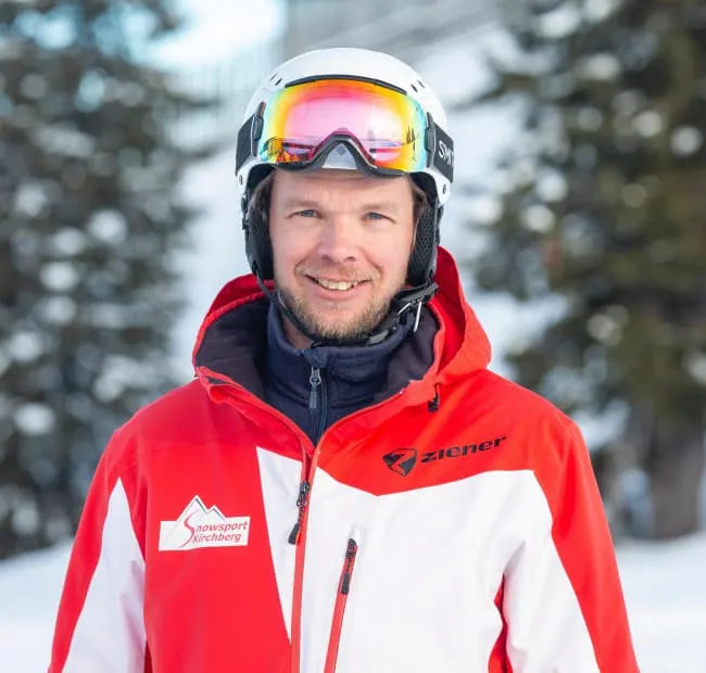 Skifahrer im Schnee mit roter Jacke und Helm