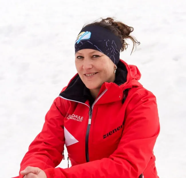 Frau in roter Jacke vor schneebedecktem Hintergrund