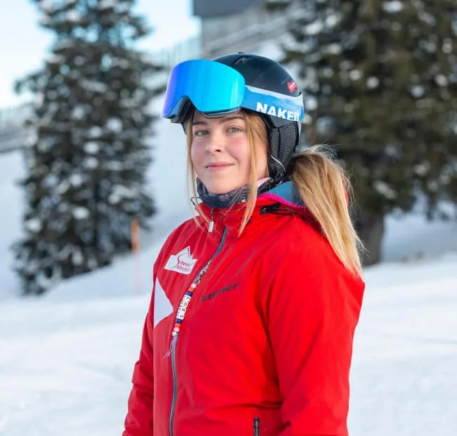 Skifahrerin in roter Jacke auf der Piste