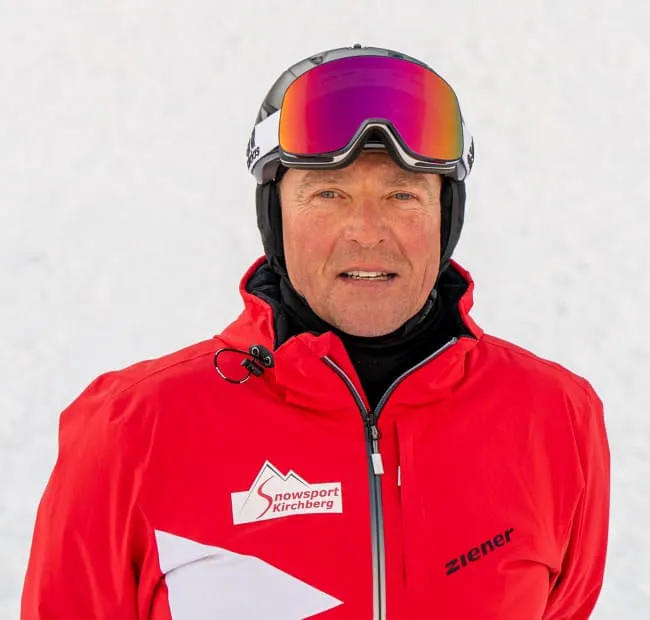 Skifahrer in roter Jacke vor schneebedecktem Hintergrund