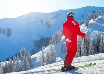 Skifahrer in roter Ausrüstung vor schneebedecktem Berg