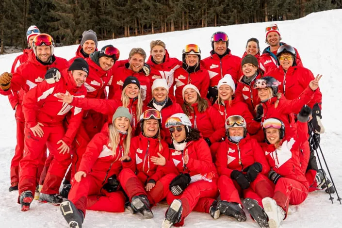 Gruppe von Skifahrern in roten Anzügen im Schnee