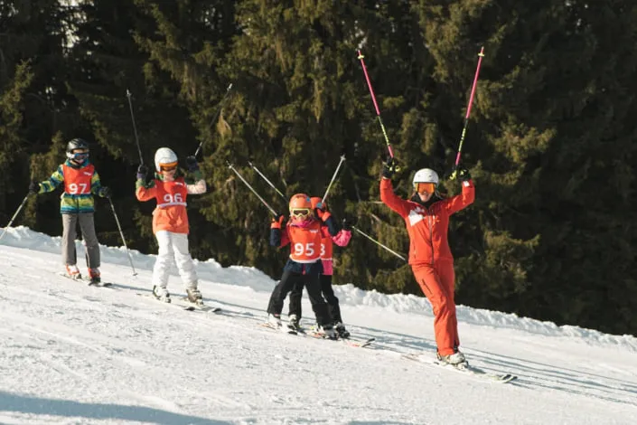 Skiende Kinder mit Lehrmeister auf verschneiter Piste